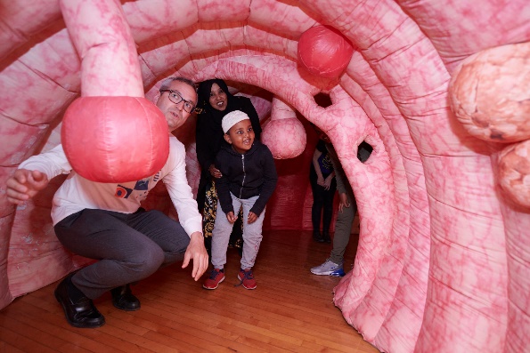 Child exploring interactive inflatable colon model at Ealing community event. 