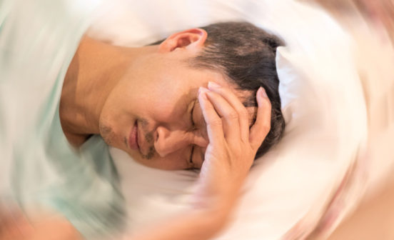 a person in bed with his hand on his forehead