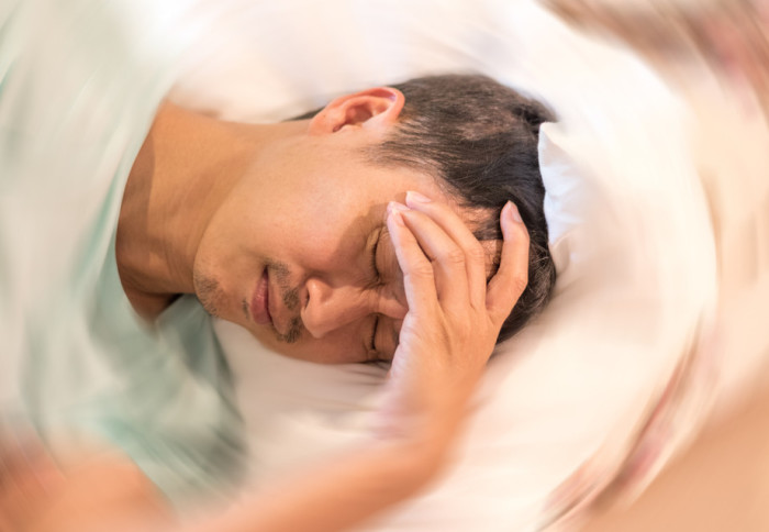 a person in bed with his hand on his forehead