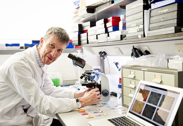 Professor Iain McNeish leaning across his work desk